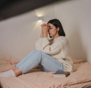 Woman in White Sweater and Blue Denim Jeans Praying on Bed